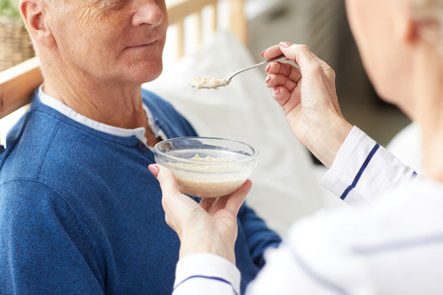 Ein Mann wird gefüttert – er benötigt ein Lätzchen für Erwachsene